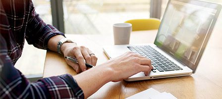 Person using laptop at wooden desk