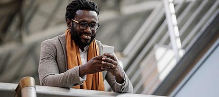Man texting on smartphone, smiling outdoors