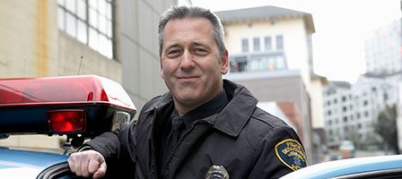 Officer posing next to police car