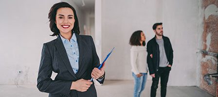 Real estate agent with clients in background