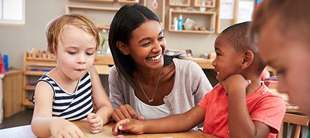 Educator engaging with children in classroom setting.