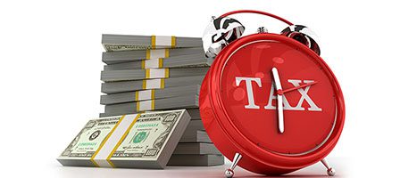 Tax-themed alarm clock and money stacks