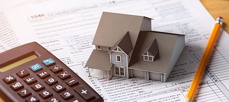 Calculator and house model on tax forms
