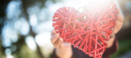 Woven red heart held in sunlight