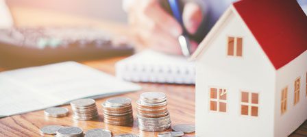Miniature house with coins and notebook