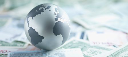 Globe on scattered currency notes background.