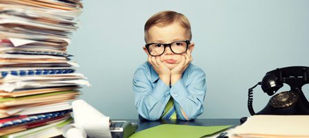 Kid at desk surrounded by documents and phone.