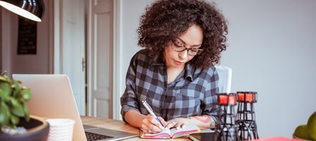 Woman writing in notebook at desk