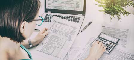 Woman doing taxes with laptop and calculator