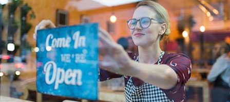 Smiling woman with open sign in shop