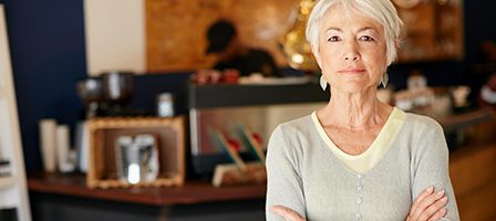 Elderly woman standing confidently in cafe