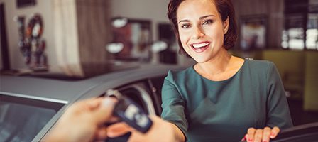 Woman receiving car keys at dealership