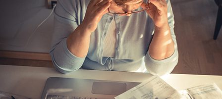 Stressed person reviewing bills at desk