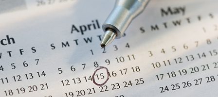 Pen pointing at circled date on calendar