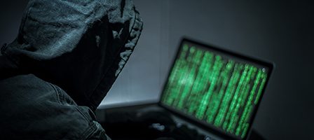 Person coding on laptop in dark