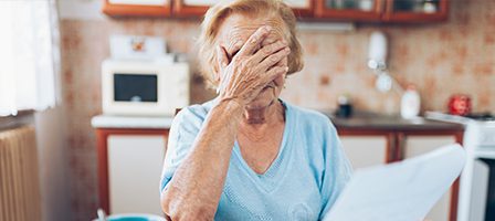 Elderly woman covering face with hand