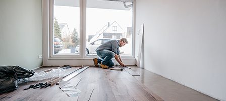 Person laying wood flooring near window