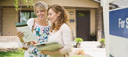 Women reviewing house plans outside home