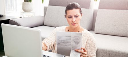 Woman working on laptop with documents