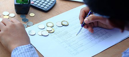Person budgeting with coins and notes