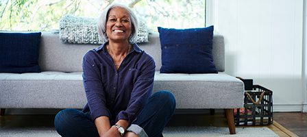 Happy woman sitting in front of sofa