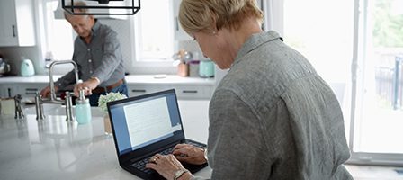 Couple multitasking in bright kitchen