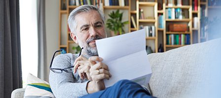 Man holding glasses and papers indoors