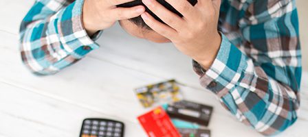 Man holding head, surrounded by credit cards