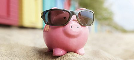 Sunglass-wearing piggy bank at seaside