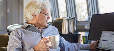 Elderly man enjoying coffee at desk