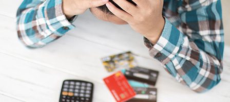 Stressed person with credit cards and calculator