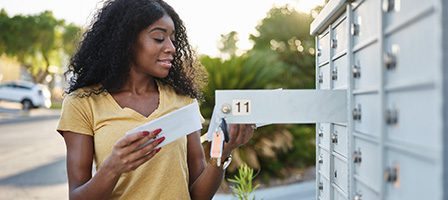 Woman checking mail at outdoor mailbox.