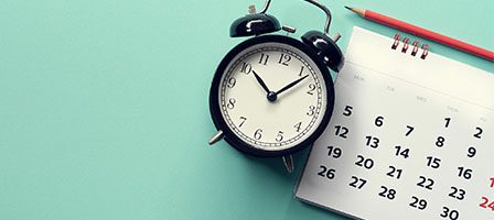 Alarm clock and calendar on turquoise background