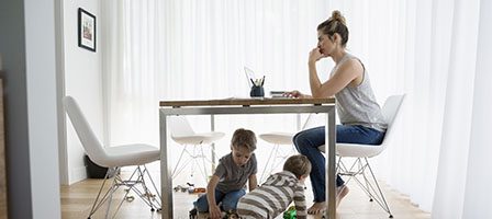 Woman working at table, kids playing below
