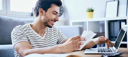 Man smiling while using laptop at home.
