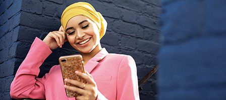 Woman smiling at phone in yellow hijab.