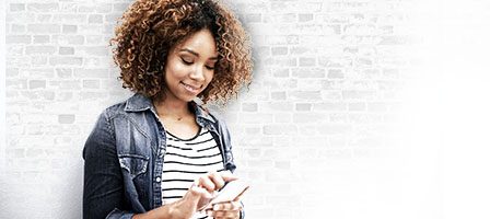 Woman using smartphone against brick wall