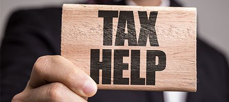 Hand holding a "Tax Help" sign