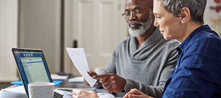 Elderly couple reviewing documents on laptop