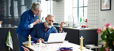 Elderly couple browsing laptop in kitchen
