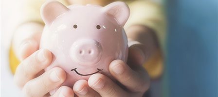 Child grasping pink piggy bank