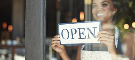 Store open sign with smiling employee