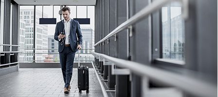 Man in suit checking phone, airport hallway