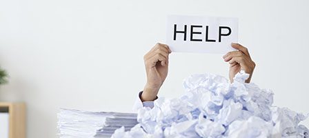 Person buried in paper clutter, asking help.