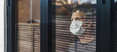 Man wearing mask looks through window