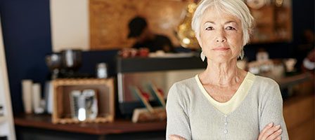 Mature woman with arms crossed in café