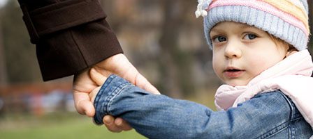 Child holding adult's hand outdoors