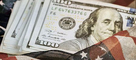 Stack of hundred dollar bills and flag