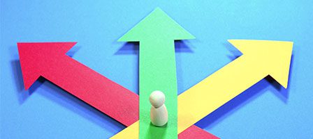 Wooden figure facing colorful directional arrows.
