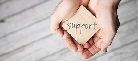Hands presenting a "support" message card